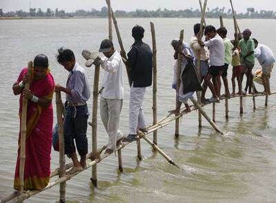 Habitantes de la localidad india de Darbhanga evacuan una zona inundada a través de un estrecho puente de bambú.