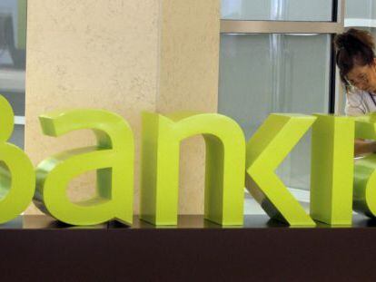 Una operaria limpia el logo de Bankia. +