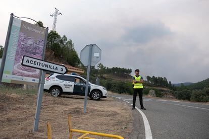 Un Guardia Civil corta el paso hacia Aceitunilla (Cáceres), uno de los pueblos desalojados. Aunque las llamas se encuentran a unos ocho kilómetros de las casas, es la presencia abundante de humo lo que impide a los vecinos volver.