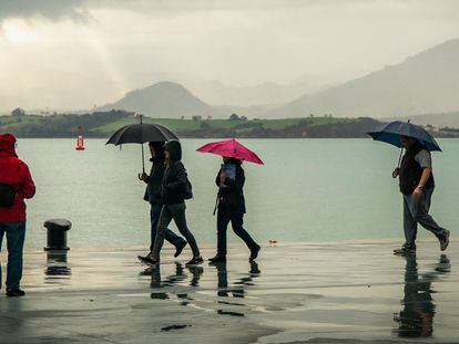 Un grupo de gente paseaba bajo la lluvia junto a la bahía de Santander, este viernes.