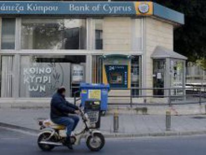 Un hombre circula ayer en motocicleta delante de una sucursal del Banco de Chipre en Nicosia (Chipre).