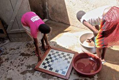 Arriba, una de las niñas residentes en Katwe. Abajo, dos aficionadas al ajedrez lavan un tablero.