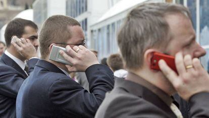 Tres hombres hablan por teléfono móvil.