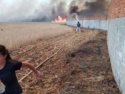 Una joven huía de las llamas mientras un vecino intentaba proteger su casa del incendio de Tábara (Zamora), el lunes.