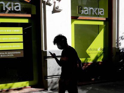 Una persona camina por el centro de Madrid delante de una sucursal de Bankia.