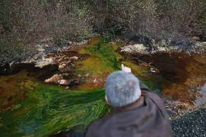 Un vecino de Touro muestra el drenaje &aacute;cido de mina en el agua de la zona.