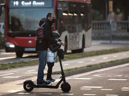 Un hombre circula con un niño en patinete, en enero.