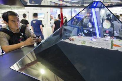 Un visitante juega con uno de los tres juegos diseñados por H+ Technology para su prototipo de videojuego holográfico.