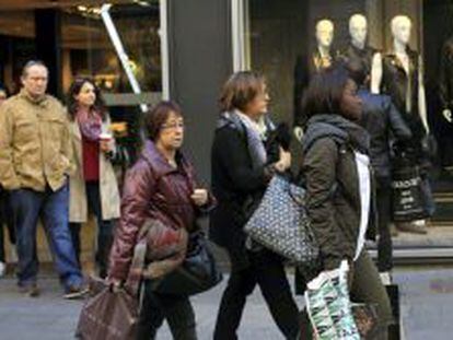 Varias personas transitan una c&eacute;ntrica calle de Barcelona tras realizar algunas compras, durante la jornada del domingo del Puente de la Constituci&oacute;n.