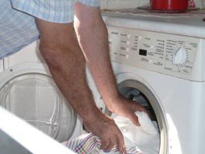 Un hombre introduce ropa en una lavadora doméstica. EFE/Archivo