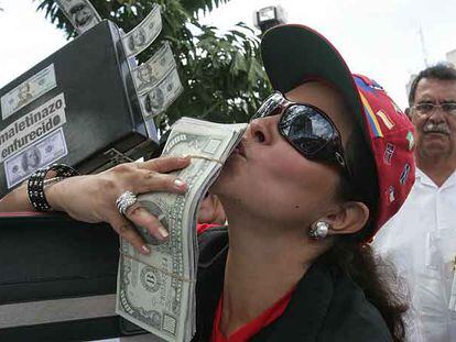 Una manifestante besa un falso fajo de dólares durante una protesta contra la corrupción ayer en Caracas.