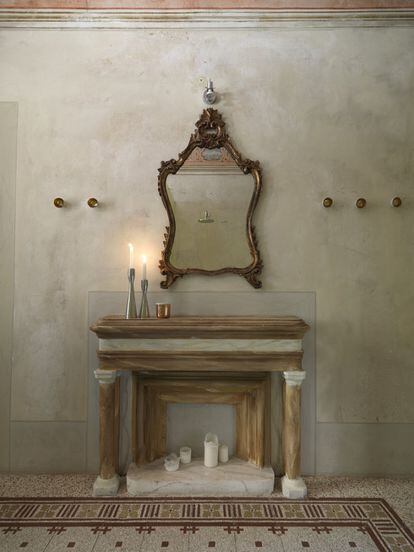 Una chimenea del siglo XVIII restaurada caldea ahora el cuarto de baño de invitados. Los candelabros son un diseño de Tom Dixon.