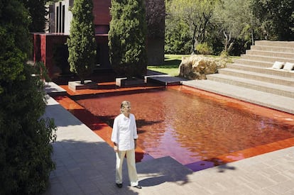 Ricardo Bofill junto a la piscina roja. Tras los cipreses la estructura cúbica acristalada, también roja, hace las veces de comedor.