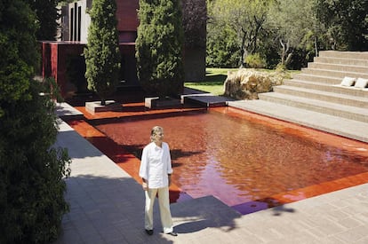 Ricardo Bofill junto a la piscina roja. Tras los cipreses la estructura cúbica acristalada, también roja, hace las veces de comedor.