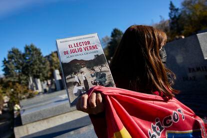 Una mujer con un libro de Almudena Grandes y una bandera del Atlético de Madrid asiste al entierro.