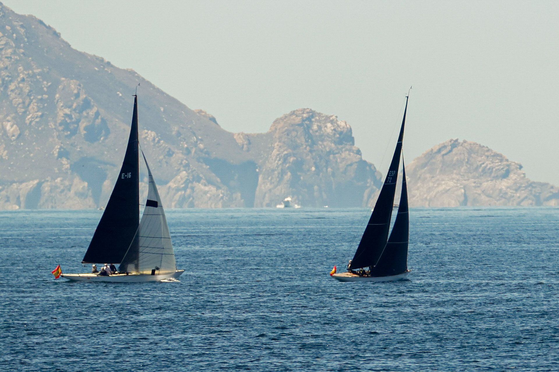 El 'Bribón 500', con el rey emérito como patrón (a la izquierda), y el 'Titia', con la Infanta Elena a bordo, compiten a finales de julio en la ría de Pontevedra, con las Islas Cíes al fondo. 