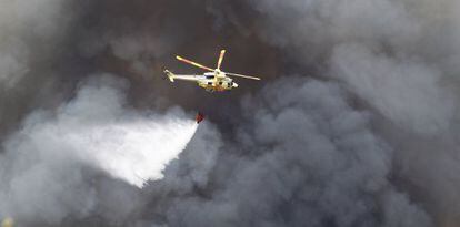 Un helic&oacute;ptero sobrevuela las &aacute;reas quemadas.