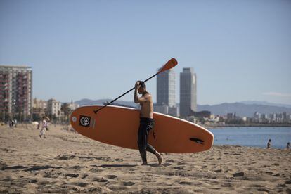 Un home amb una taula de pàdel surf aquest dimarts a la platja de la Barceloneta.