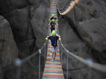 Varias personas cruzan un puente colgante de las Lomas del Mirador, en San Juan de Lurigancho (Perú).