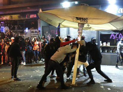 Un grupo de jóvenes rompe este sábado una sombrilla en el centro de Barcelona. En vídeo, las imágenes desde el furgón durante la noche del viernes.