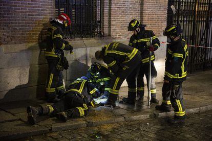 Un grupo de bomberos del Ayuntamiento de Madrid trabajan en una zona cercana al lugar donde se ha producido una explosión para cortar el agua que abastece al edificio siniestrado.