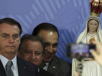 Bolsonaro posa para una foto con una imagen de la virgen de Fátima al fondo.