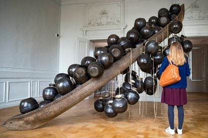Una visitante observa la obra "Jal Mein Kumbh, Kumbh Mein Jal Hai" del artista indio Subodh Gupta en una retrospectiva de su trabajo en el museo Monnaie de París (Francia), el 10 de abril de 2018. La muestra abre al público desde el 13 de abril hasta el 26 de agosto.