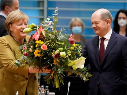 La canciller alemana en funciones, Angela Merkel, recibe un ramo de flores de su previsto sucesor, Olaf Scholz, esta mañana antes del que probablemente sea su último Consejo de Ministros.