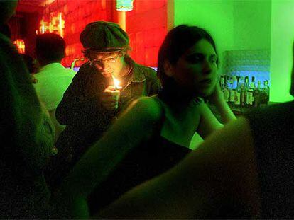 Un cliente enciende un cigarrillo en un bar musical en Barcelona.