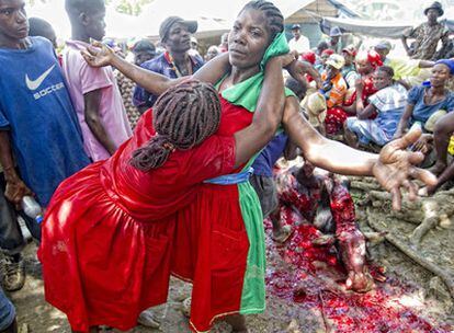Ritual con sacrificios. El matarife degüella a la vaca y un chorro de sangre salpica al grupo mientras la santera es abrazada por otra mujer.