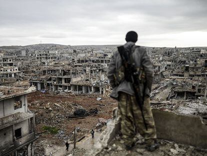Un miliciano kurdo observa la aldea destruida de Halimce, al este de la ciudad siria de Kobane, en enero de 2015.