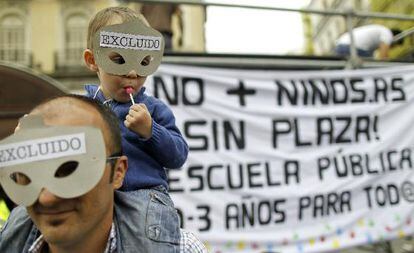 Un hombre porta sobre sus hombros a un niño ante una pancarta que reclama la extensión de la enseñanza pública gratuita en Sol.