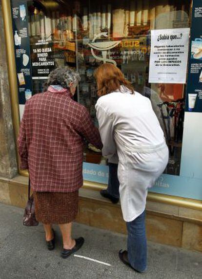 Carteles de protesta por la deuda de la Generalitat en una farmacia valenciana