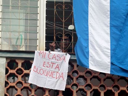 El disidente cubano Yunior García mira por la ventana de su vivienda con un cartel que indica "Mi casa está bloqueada'', el 14 de noviembre en La Habana.