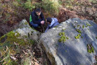 Dos miembros de MariñaPatrimonio, junto a las piedras de la mámoa que están a la luz.