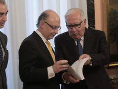 El presidente del comité de expertos para la reforma fiscal, Manuel Lagares (d), entrega al ministro de Hacienda, Cristóbal Montoro (c), el informe en la sede del Ministerio de Hacienda en Madrid.