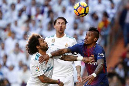 El defensa brasileño del Real Madrid, Marcelo Vieira, y el mediocampo brasileño del FC Barcelona, Paulinho Bezerra, saltan por el balón ante el defensa del Real Madrid, Sergio Ramos.