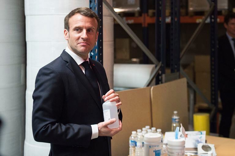 El presidente francés, Emmanuel Macron, sostiene una botella de gel hidroalcohólico durante su visita a una fábrica en Francia que produce mascarillas.