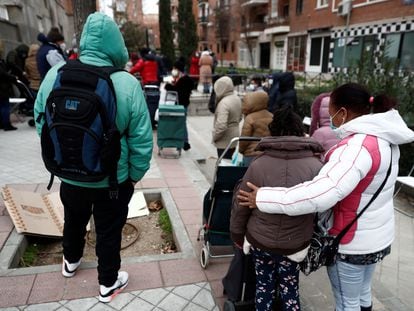 Varias personas esperan su turno para recibir alimentos, en la plaza de San Amaro en Madrid.