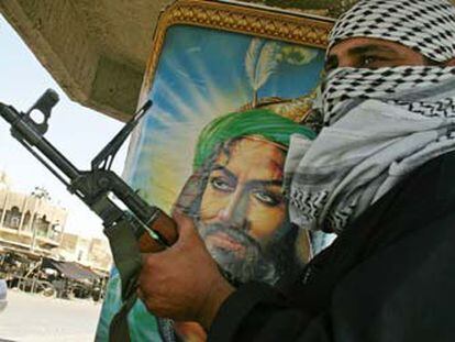 Un miliciano chií sujeta su arma junto a un retrato del imán Alí, en una calle de Bagdad.