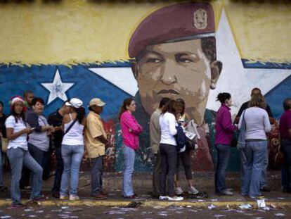Cola en Caracas ante un mural de Hugo Ch&aacute;vez.