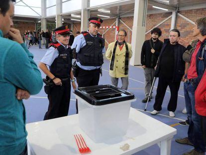 Dos mossos ante una urna de un colegio durante la jornada del referéndum del 1 de octubre en Cataluña.