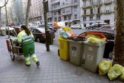 Una limpiadora del Ayuntamiento de Madrid pasa junto a varios contenedores de basura en una calle del centro de Madrid. EFE/Archivo