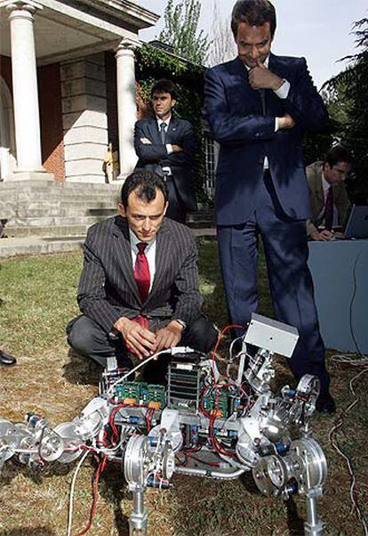 Duque, agachado, observa un prototipo junto a Zapatero.