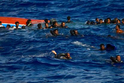 Los migrantes que navegaban en la embarcación permanecen en el agua mientras esperan a ser rescatados por miembros de Open Arms.