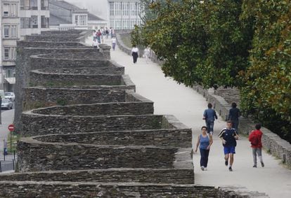 Un grupo de personas pasea por el adarve de la muralla romana de Lugo. 