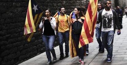 Un grupo de personas caminan por Barcelona con banderas catalanas.