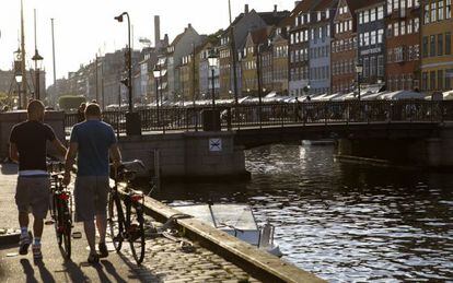 Dos ciclistas paseando junto a uno de los canales de Copenhague.