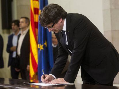 El presidente de la Generalitat, Carles Puigdemont, firma el documento sobre la Independencia en el Parlament. EFE/Quique García