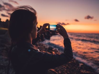 Una mujer utiliza la cámara de su móvil para fotografiar el atardecer.